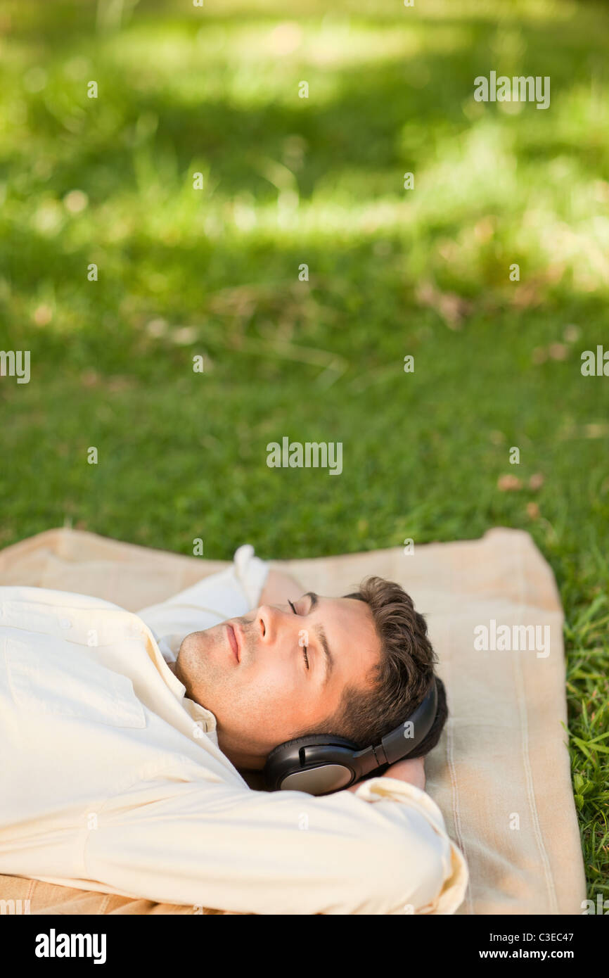 Joven escuchando música en el parque Foto de stock