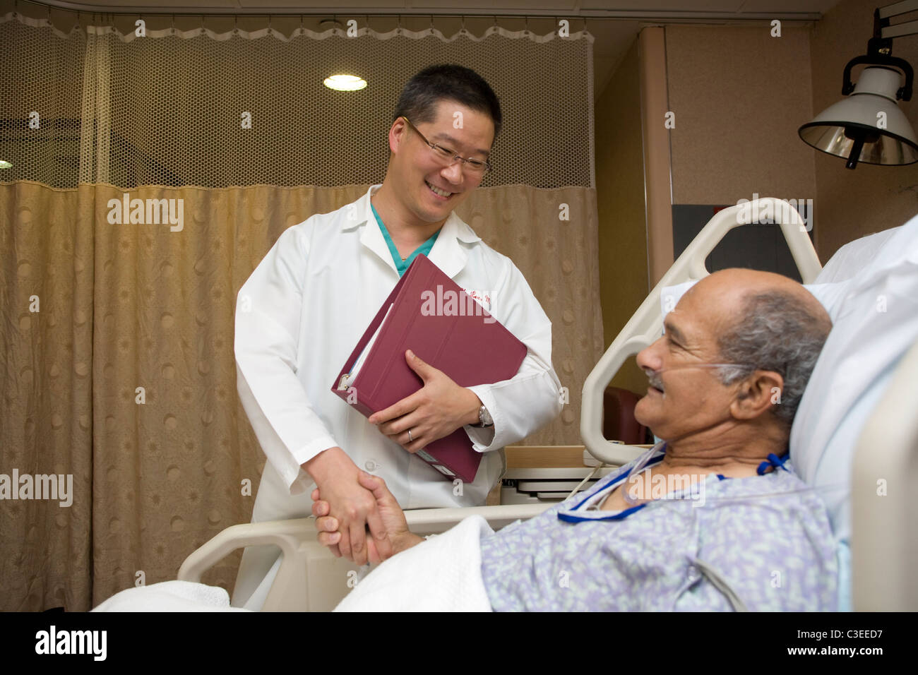 Doctor tranquiliza a pacientes de más edad que él está haciendo bien después de la cirugía. Foto de stock