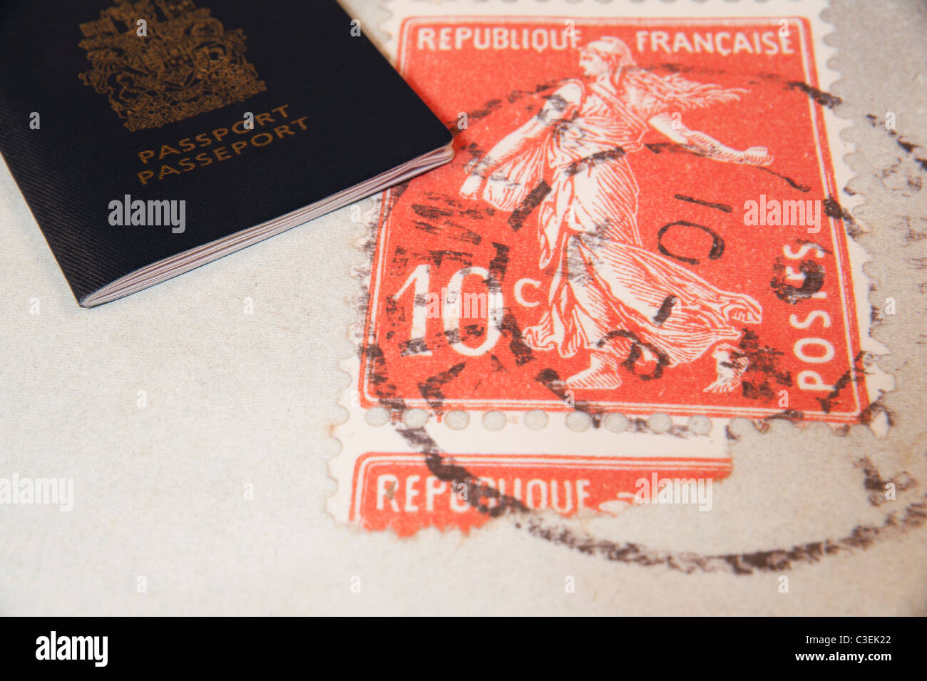 Pasaporte canadiense acostado en francés Travel cartel junto a un sello de correos, en representación de viajes y oportunidades. Foto de stock