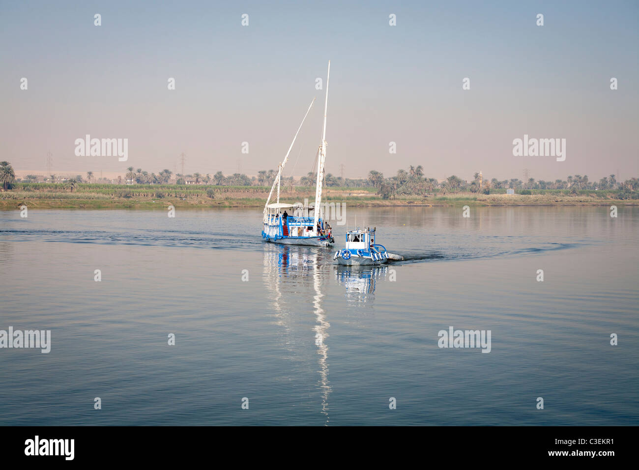 Una dahabiya siendo remolcado por pequeñas embarcaciones por el río Nilo en aguas tranquilas, Egipto, África Foto de stock