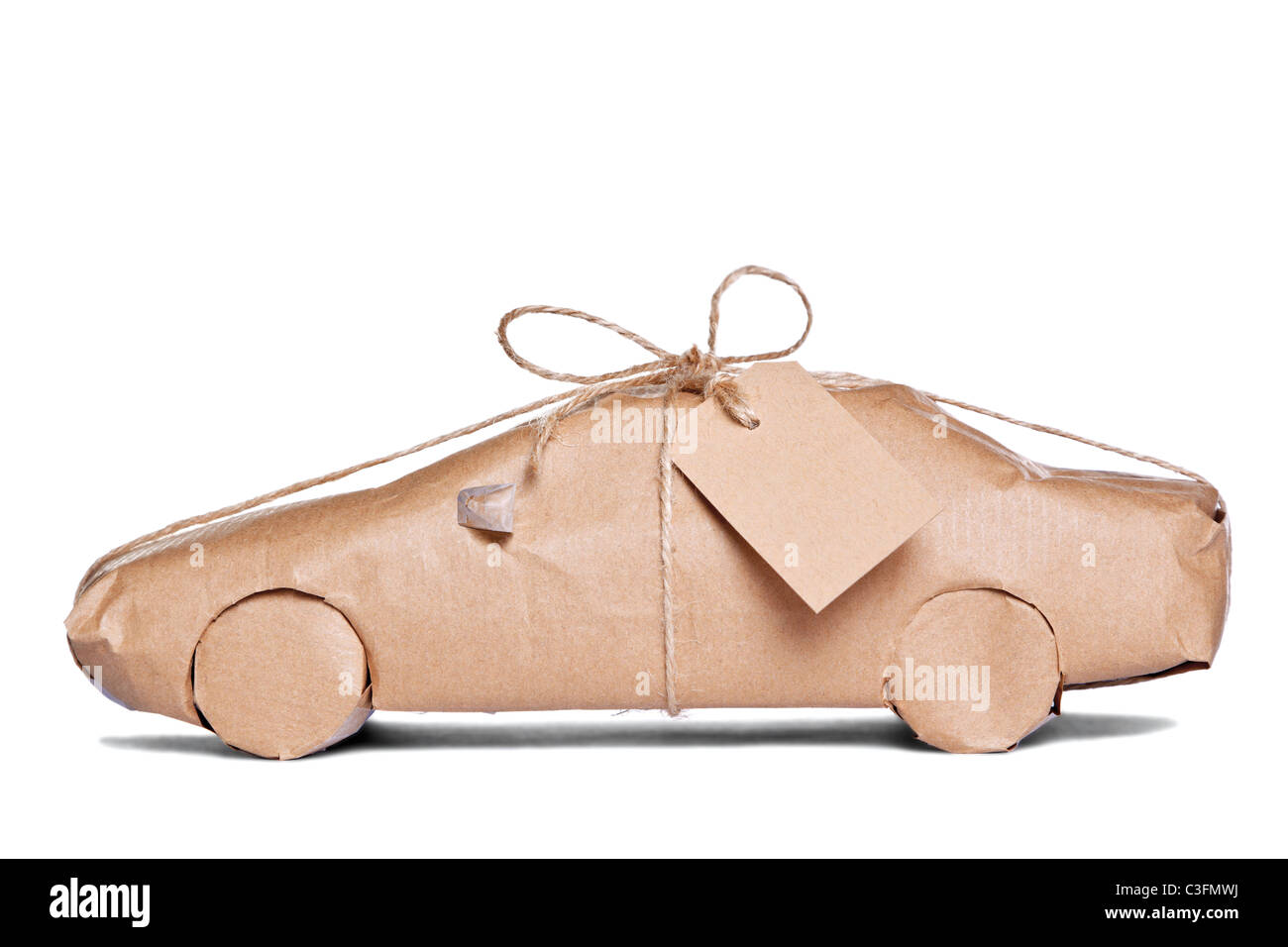 Foto de un coche envuelto en papel reciclado marrón con etiqueta, recortadas sobre un fondo blanco. Foto de stock
