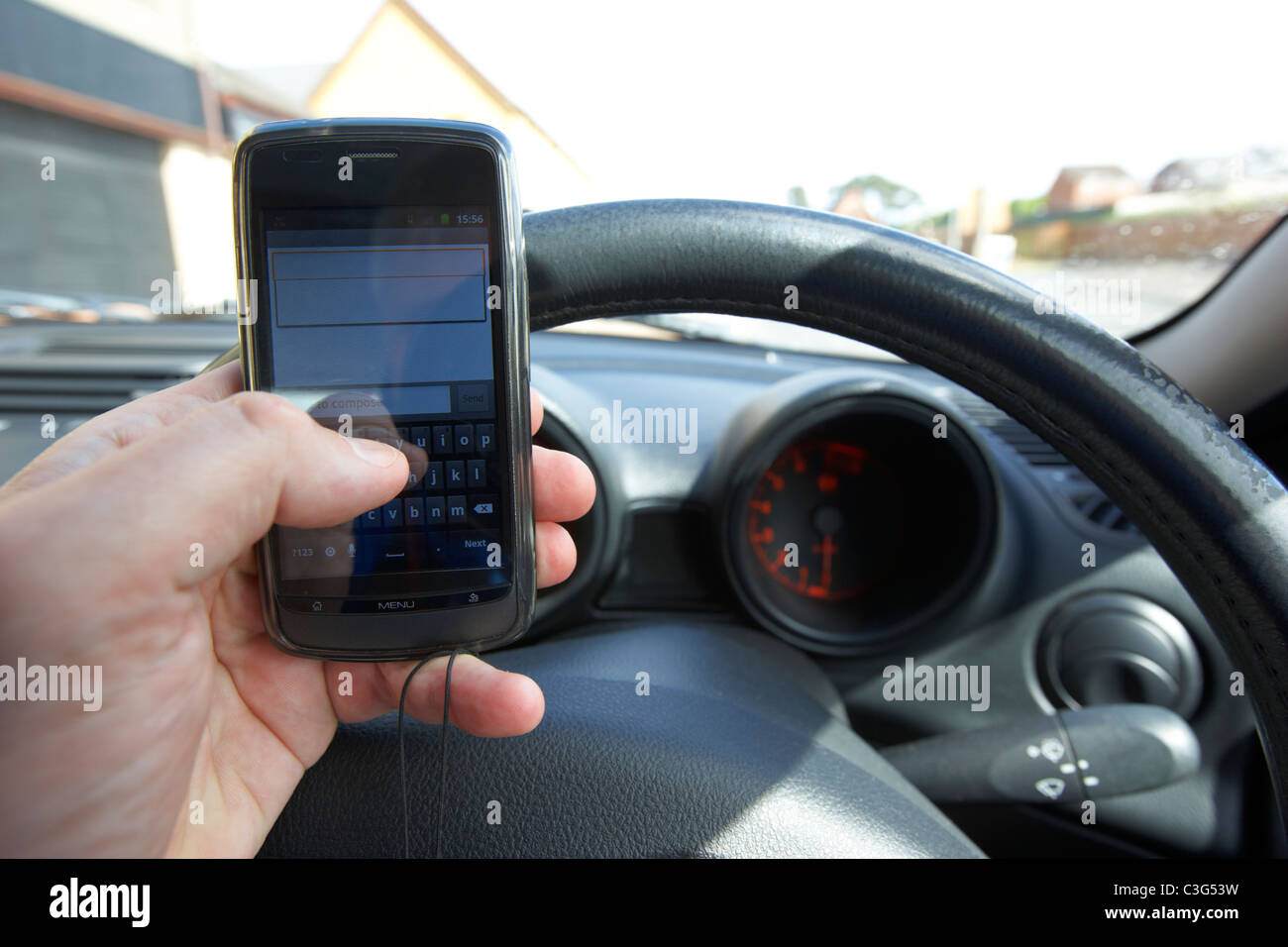 El hombre mediante la pantalla táctil del teléfono móvil Android para enviar un mensaje de texto al conducir Foto de stock