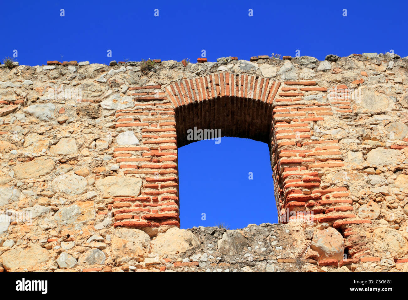 Arco rebajado de ladrillo en el antiguo muro de piedra de mampostería España Foto de stock