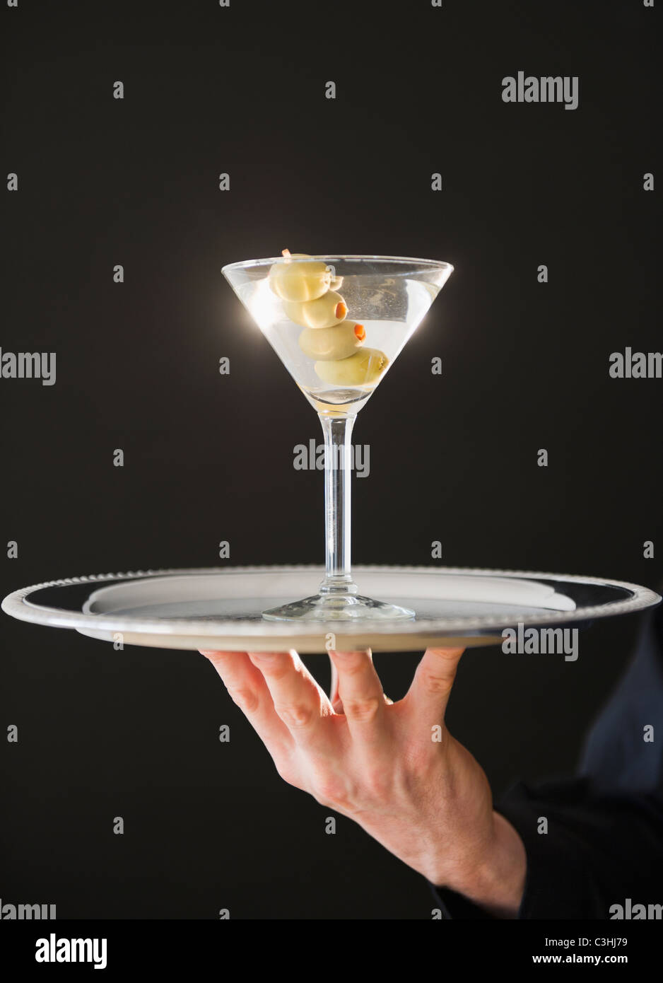 Mano sujetando la bandeja con el martini Foto de stock
