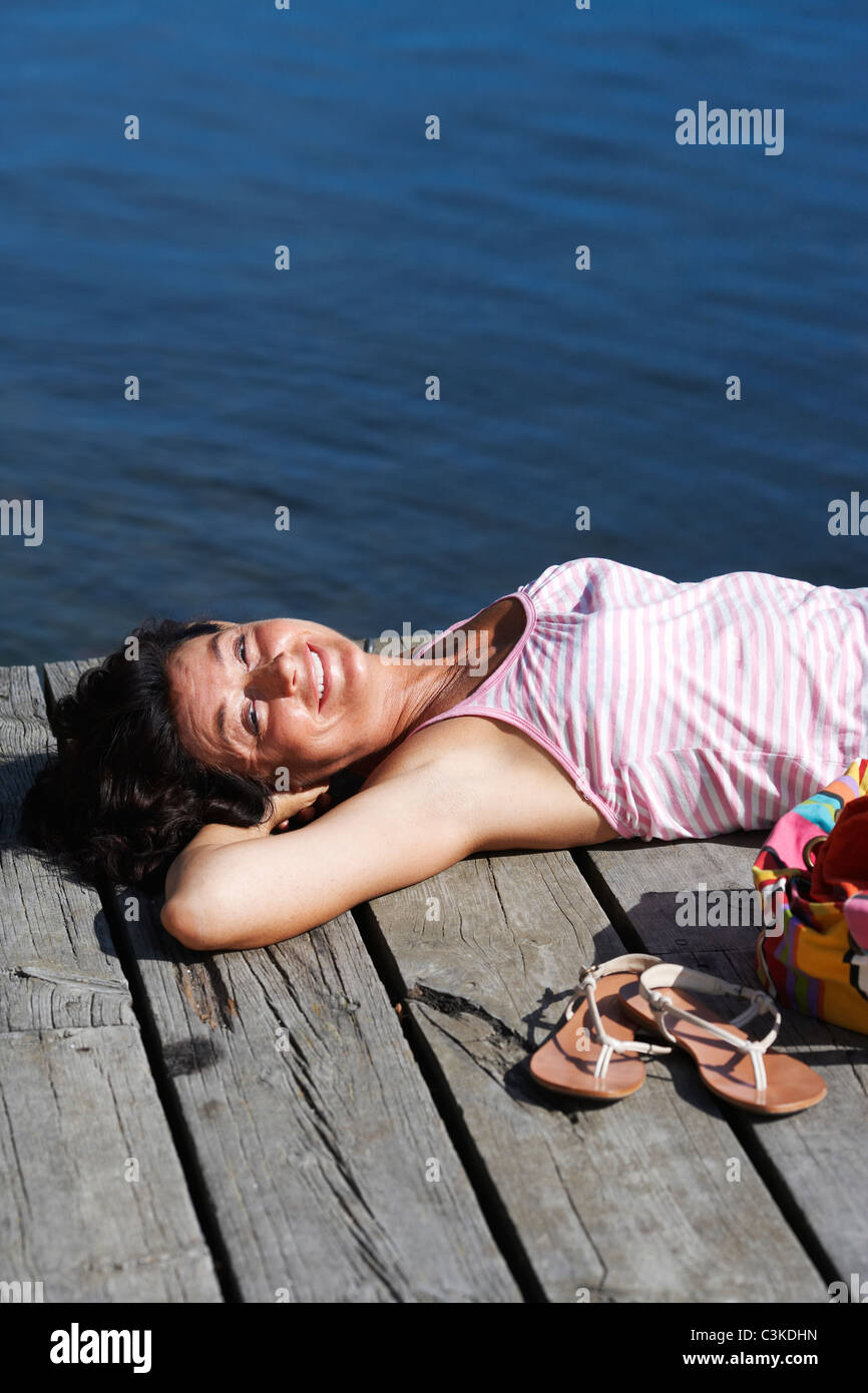 Una mujer en un embarcadero a orillas de un lago, Suecia. Foto de stock