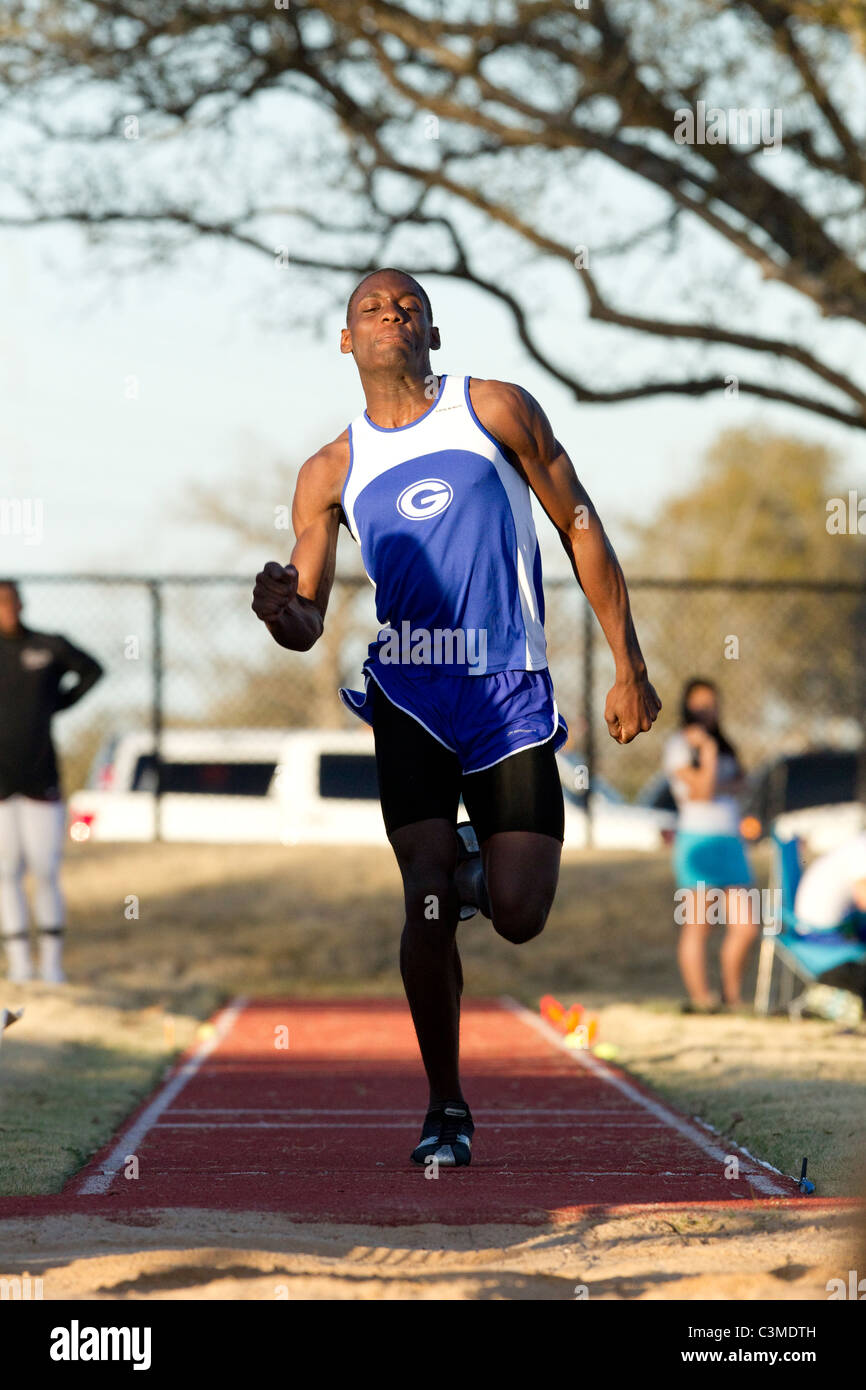 Atleta Masculino afroamericano enfoques despegue en el salto de longitud en la escuela secundaria vía reunirse en San Antonio, Texas Foto de stock