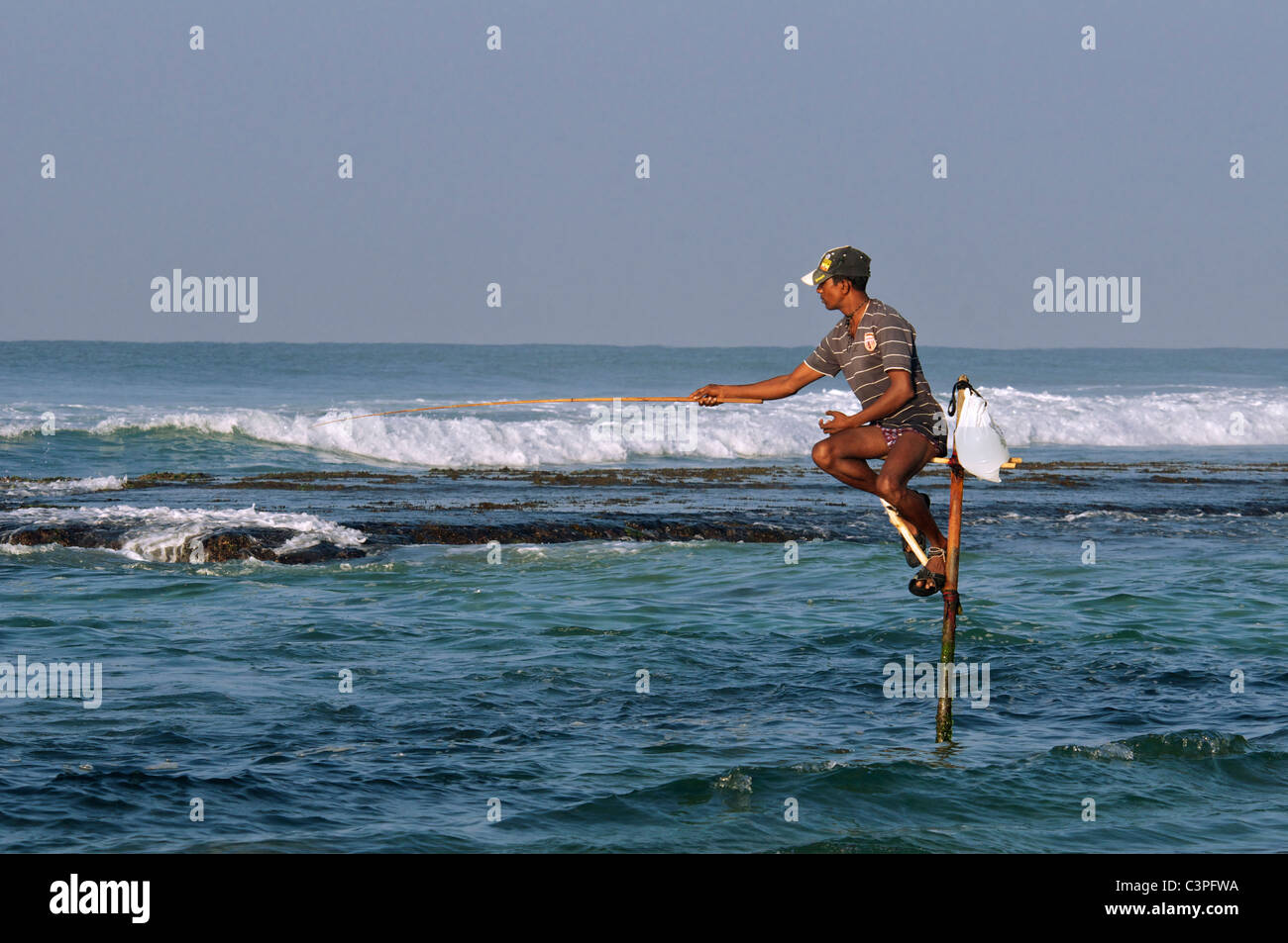 Pescador en el poste de la luz de la mañana temprano Koggala Beach costa sur de Sri Lanka Foto de stock