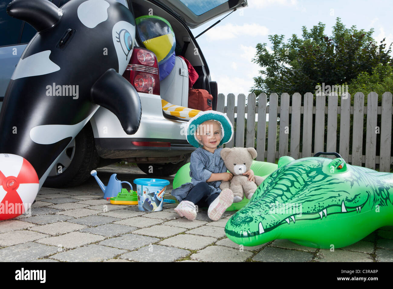Alemania, Munich, Niña (2-3 años) que sujetan el juguete blando y sentado detrás de coches Foto de stock
