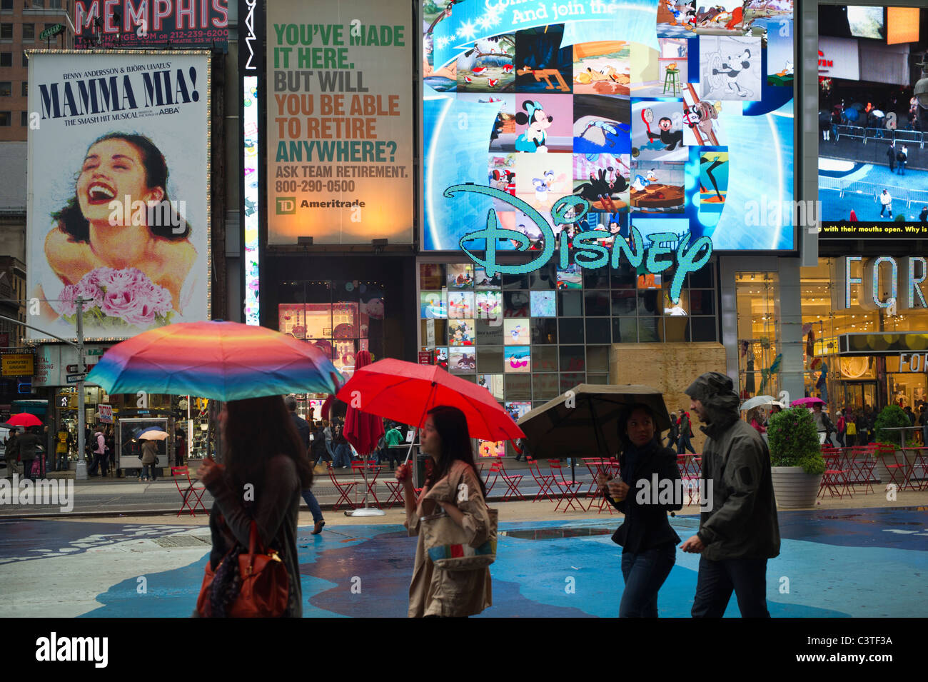 Los turistas llevar paraguas pasar las vallas de musicales de Broadway y Disney  Store en un día lluvioso en Times Square en Nueva York Fotografía de stock  - Alamy
