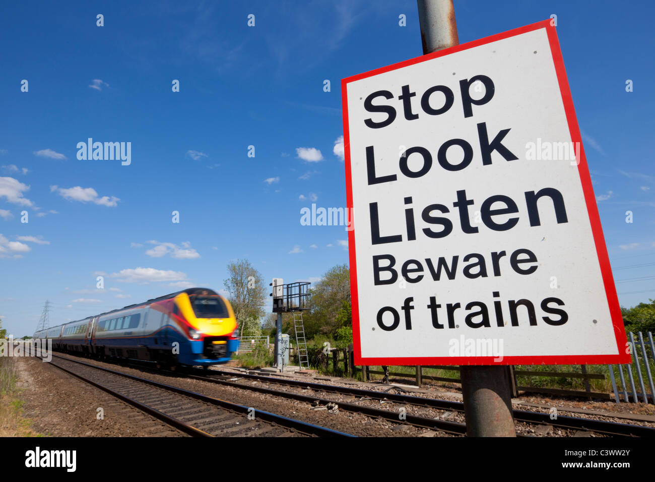 Pare mire escuche cuídese de trenes firmar por un tren a toda velocidad pasando un cruce ferroviario signo de advertencia de Inglaterra GB UK Europa Foto de stock