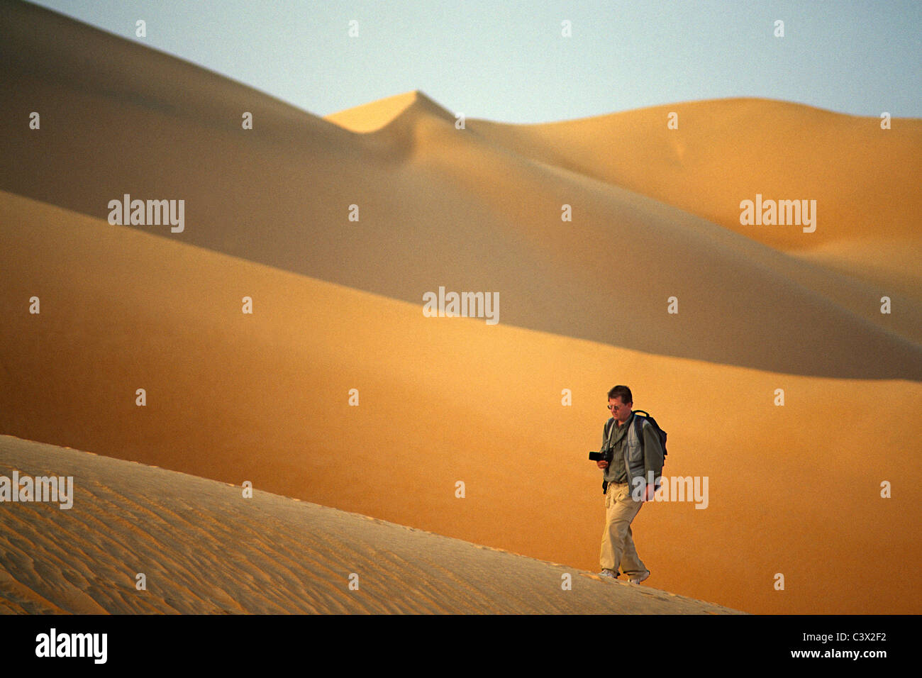 Argelia, Djanet, el desierto del Sahara, el fotógrafo Frans Lemmens caminando sobre una duna de arena. Foto de stock