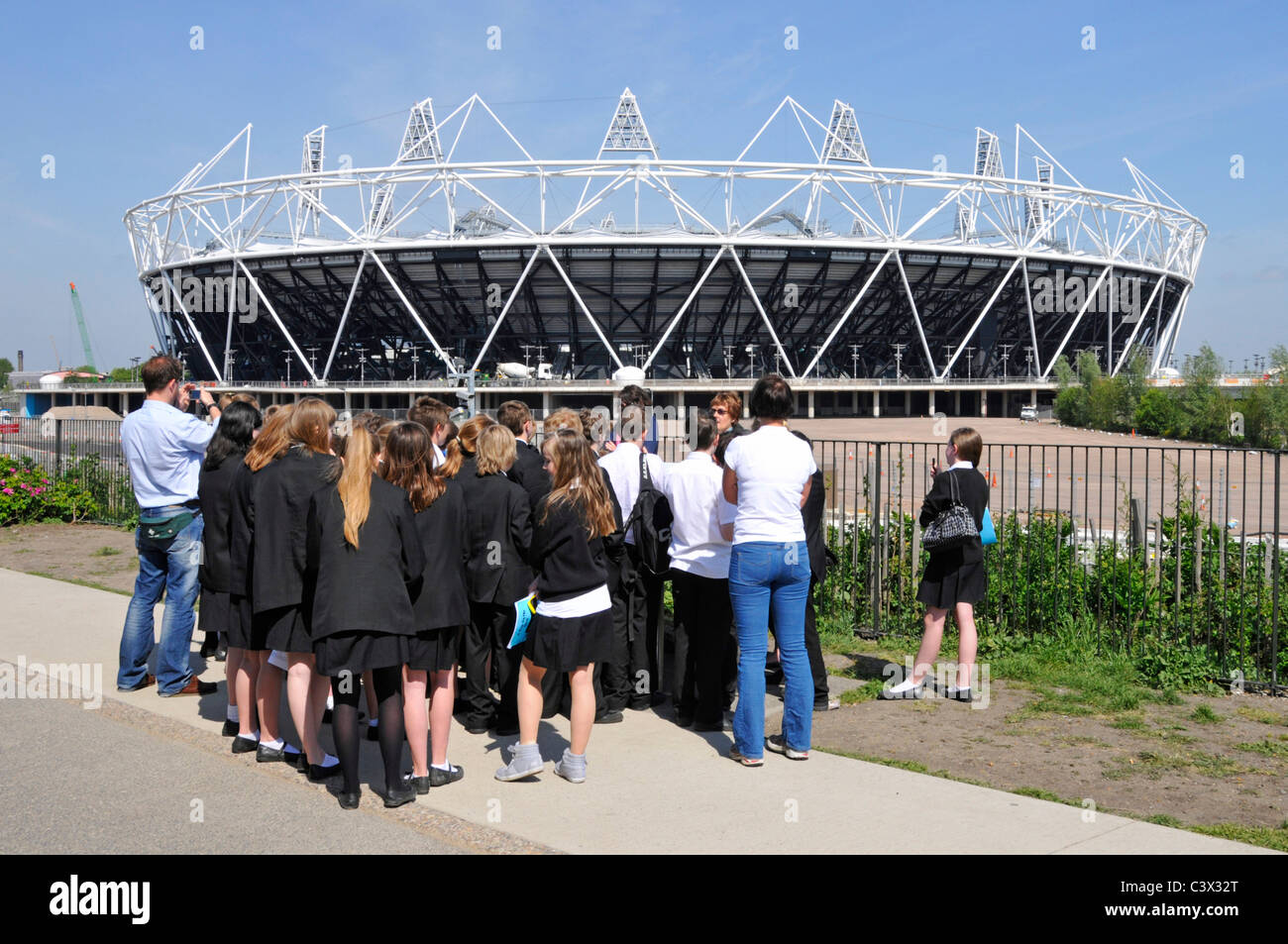 Viaje escolar al Parque Olímpico de Londres los alumnos escuchar guía local. Foto de stock