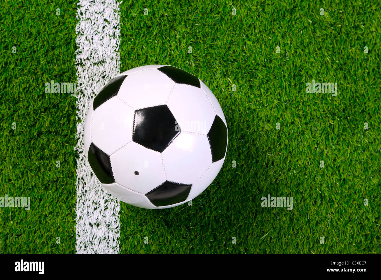 Foto de un cuero de fútbol o una pelota de fútbol sobre un césped junto a la línea blanca, tomada desde arriba. Foto de stock