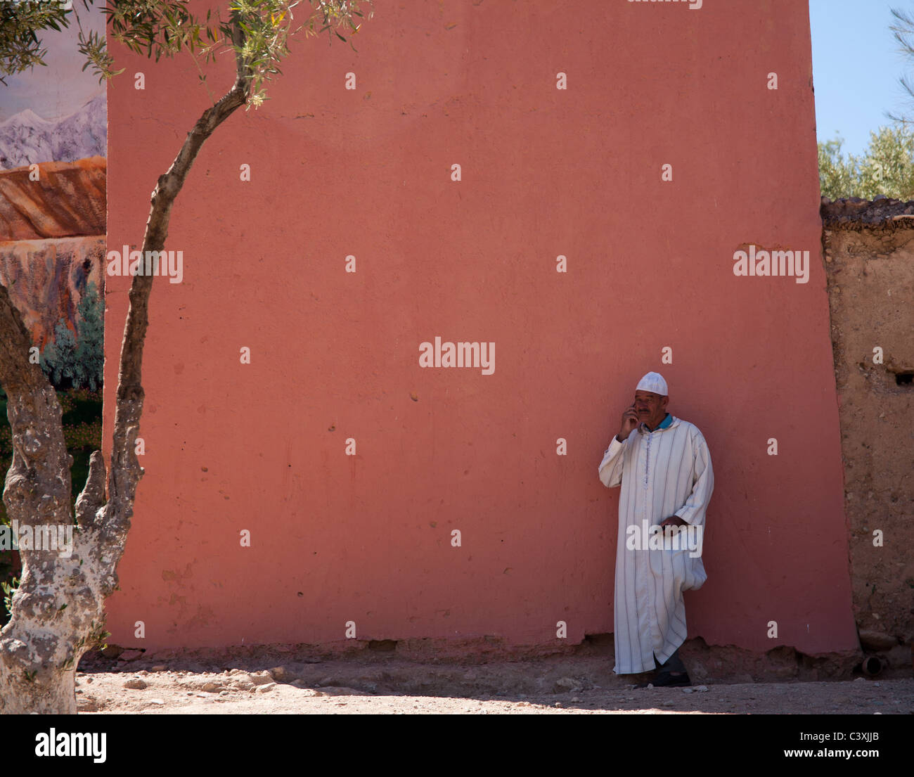 Hombre de pie junto a una pared de ladrillo rojo Kelaa M'Kouna Foto de stock