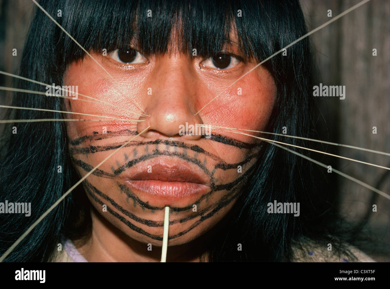 Pintura roja y negra cubre un Matses cara de mujer, y ella lleva espinas  decorativos en ambos lados de la nariz Fotografía de stock - Alamy