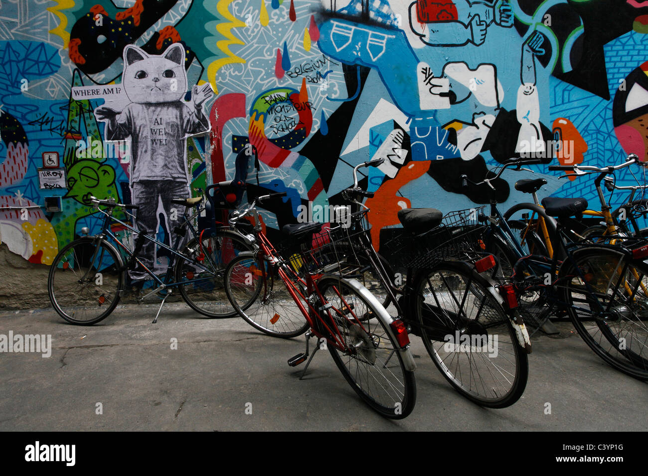 Bicicletas estacionadas junto a una pared cubierta de pared pintada en el distrito central de Mitte de Berlín, Alemania Foto de stock