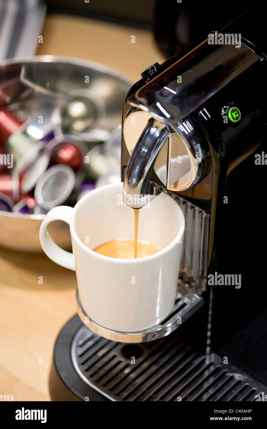 Cerca de la máquina de café Nespresso brewing recién nuevo expreso.  Cápsulas de café en un recipiente en el fondo Fotografía de stock - Alamy