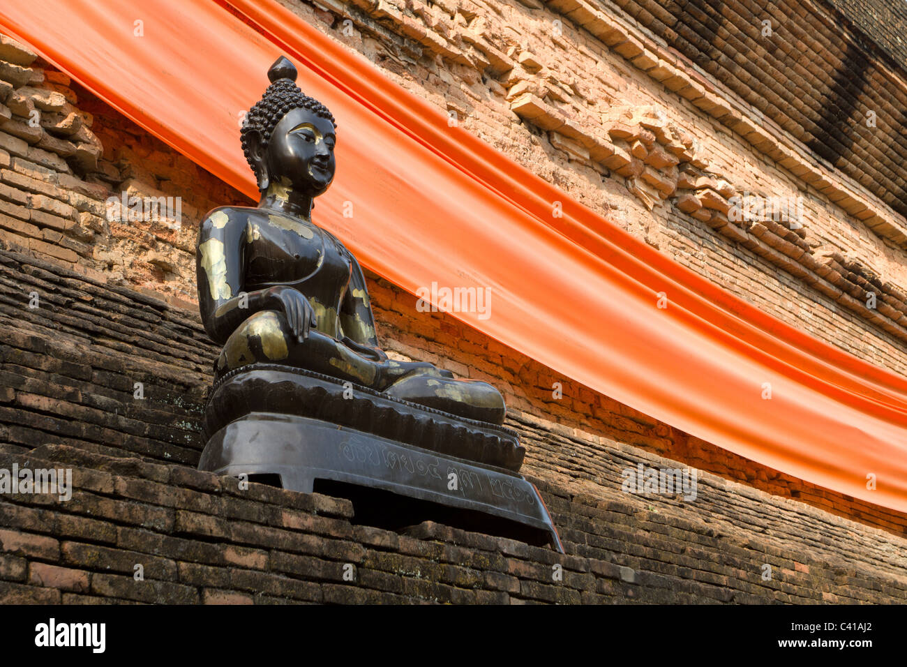 Estatua de buda negro metalizado en una pared de ladrillo antiguo, Chian Mai, Tailandia Foto de stock