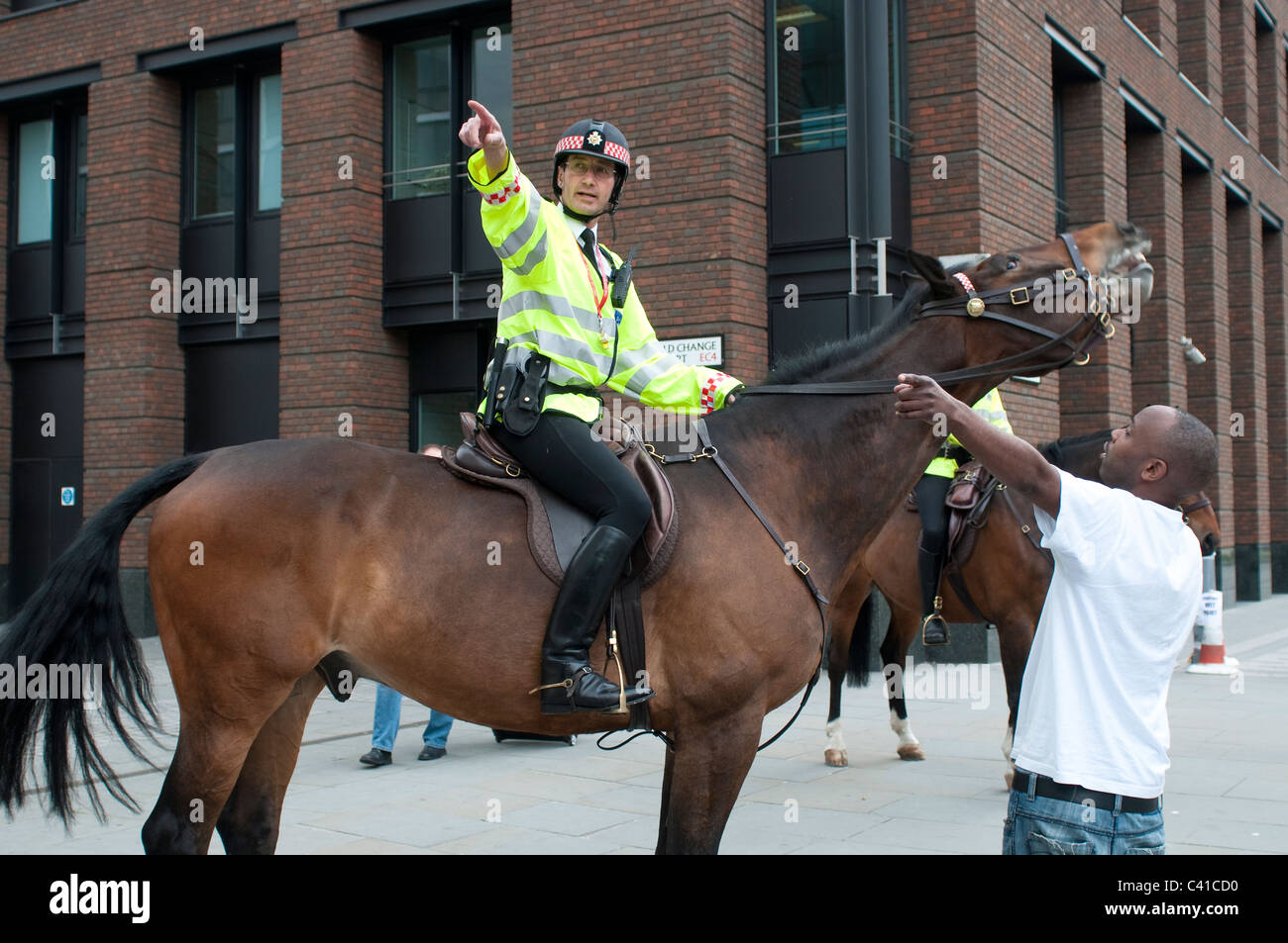 Policía Montada que muestra las direcciones a un hombre negro, de la ciudad de Londres, Reino Unido Foto de stock