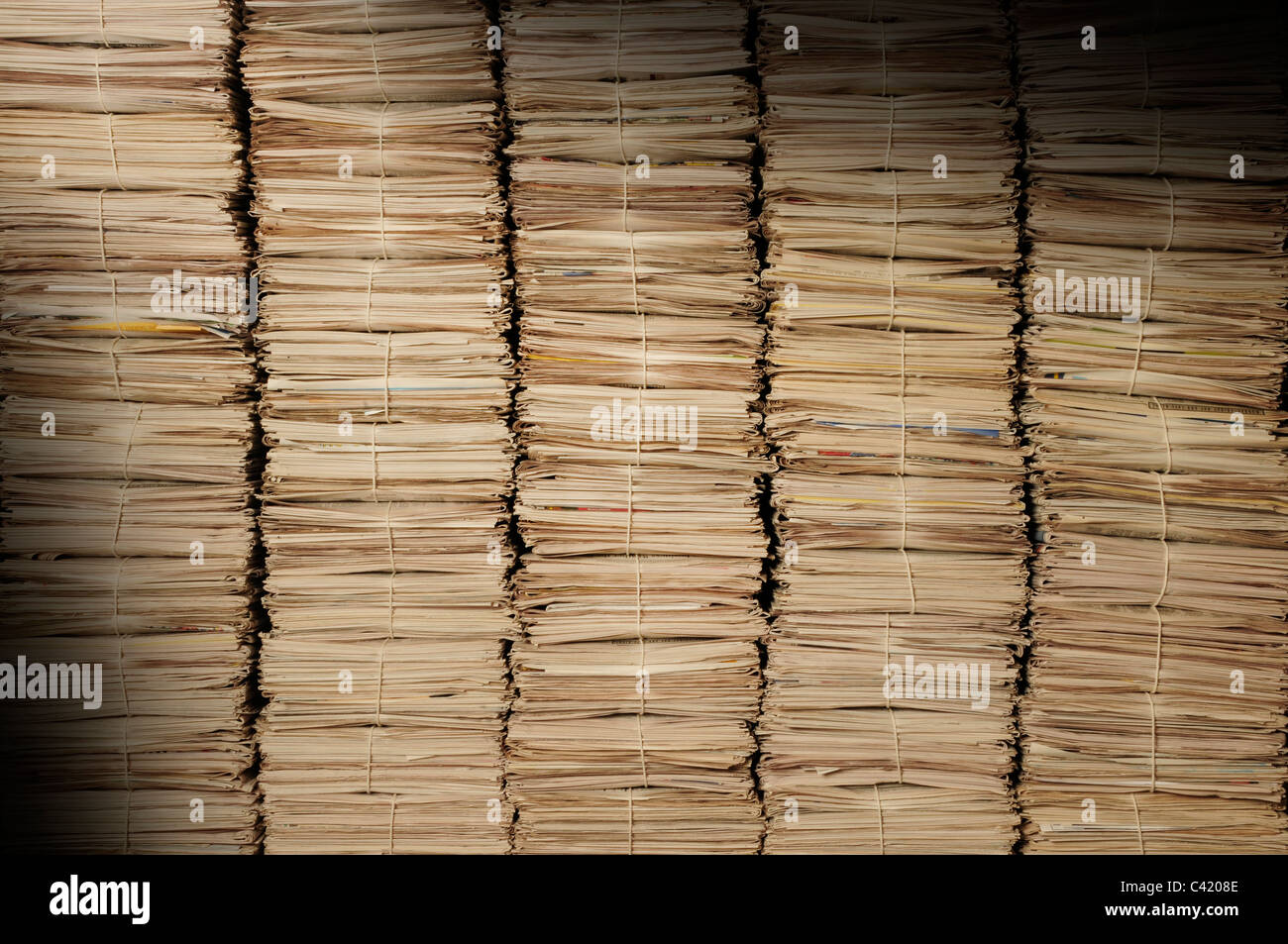 Cinco montones de periódicos uniforme para ser reciclados iluminados en diagonal. Foto de stock