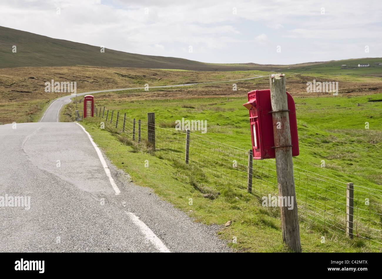 Voe, Northmavine, Islas Shetland, Escocia, Reino Unido, Europa. Single track country road y rojo Royal Mail postbox en un post wonky. Foto de stock