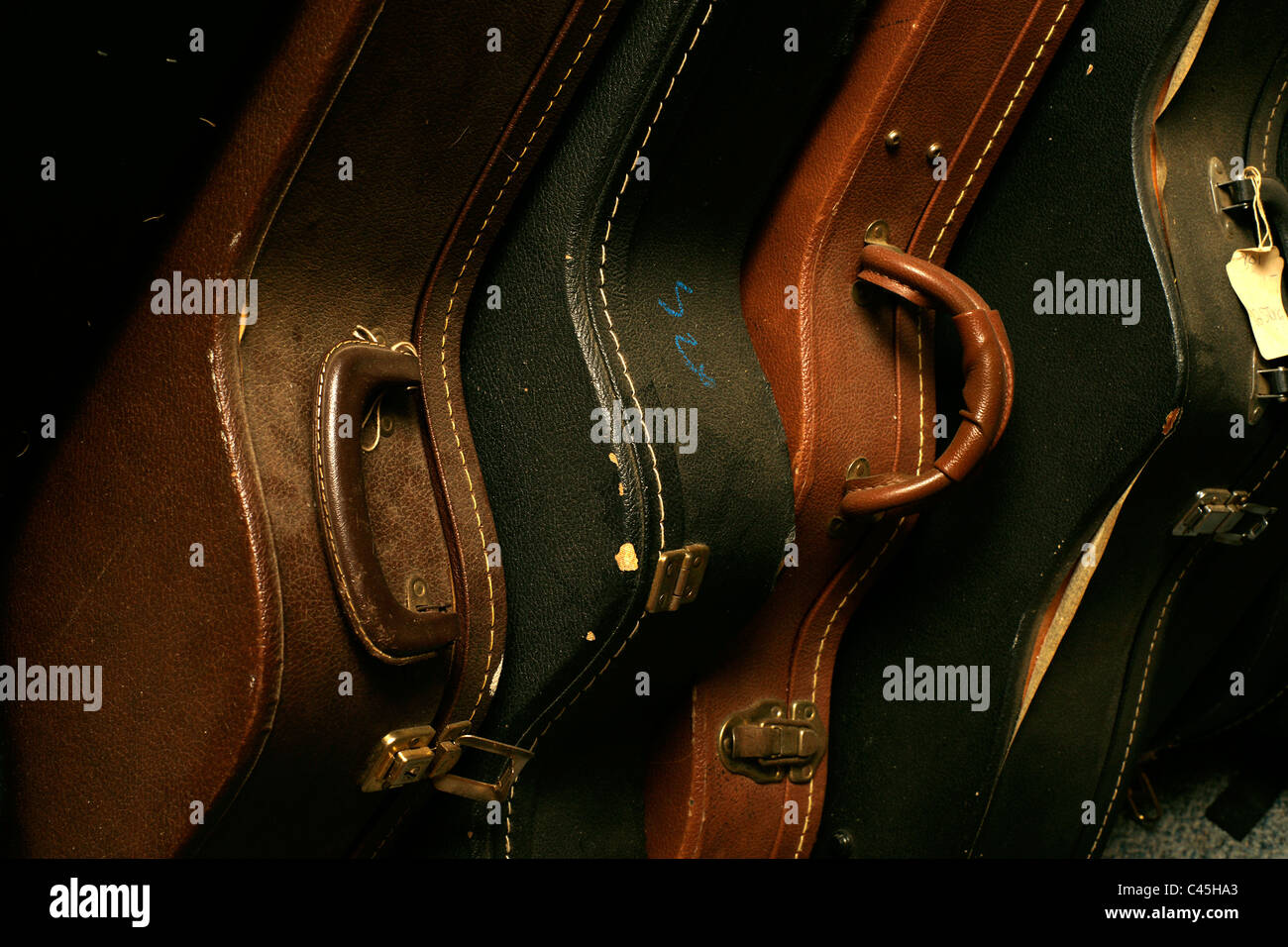 Close-up de una fila de apilado, vieja y gastada guitarra de casos. Foto de stock