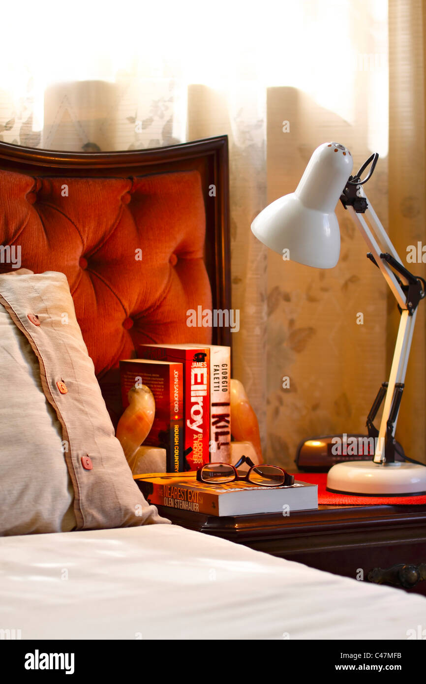 Resumen de la cama y el cabecero de la cama con lámpara de mesilla y libros. Foto de stock