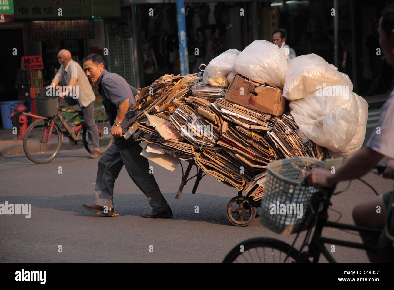 Hombre saca la cesta llena de productos reciclables, Guangzhou, China Foto de stock