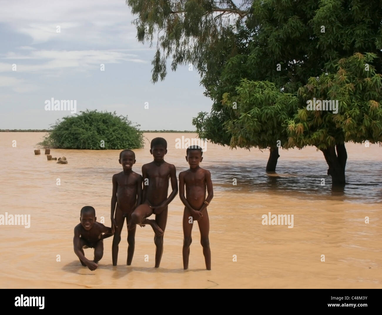 Cuatro niños Songhai africanos desnudos de pie en el borde de un gran lago,  Gossi sucio, Malí, África occidental Fotografía de stock - Alamy