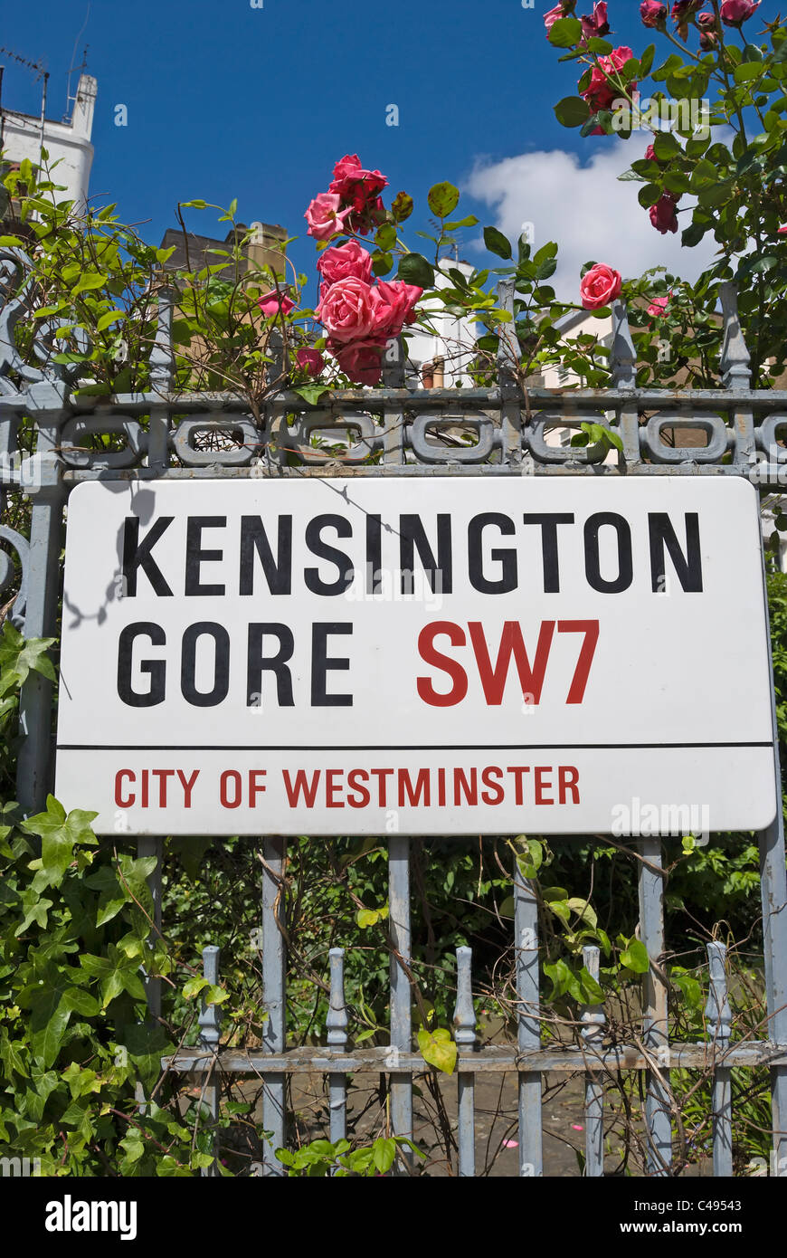 El nombre de la calle para firmar Kensington Gore, Londres, Inglaterra, en barandillas respaldado por rosas y follaje colorido Foto de stock