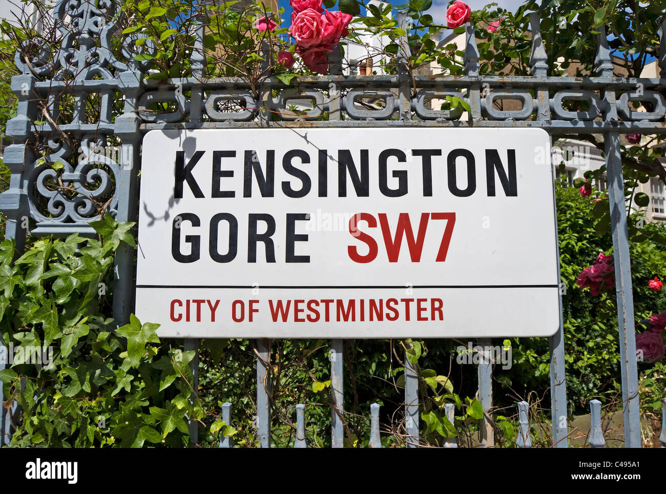 El nombre de la calle para firmar Kensington Gore, Londres, Inglaterra, en barandillas respaldado por rosas y follaje colorido Foto de stock