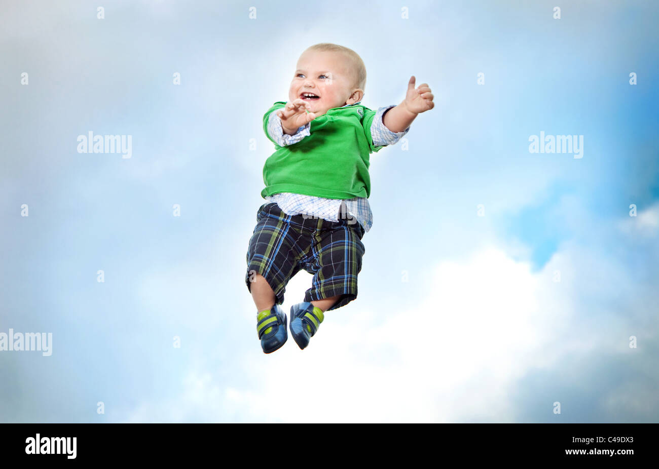 Un niño en ropa moderna volando en mitad del aire contra un cielo azul. Foto de stock