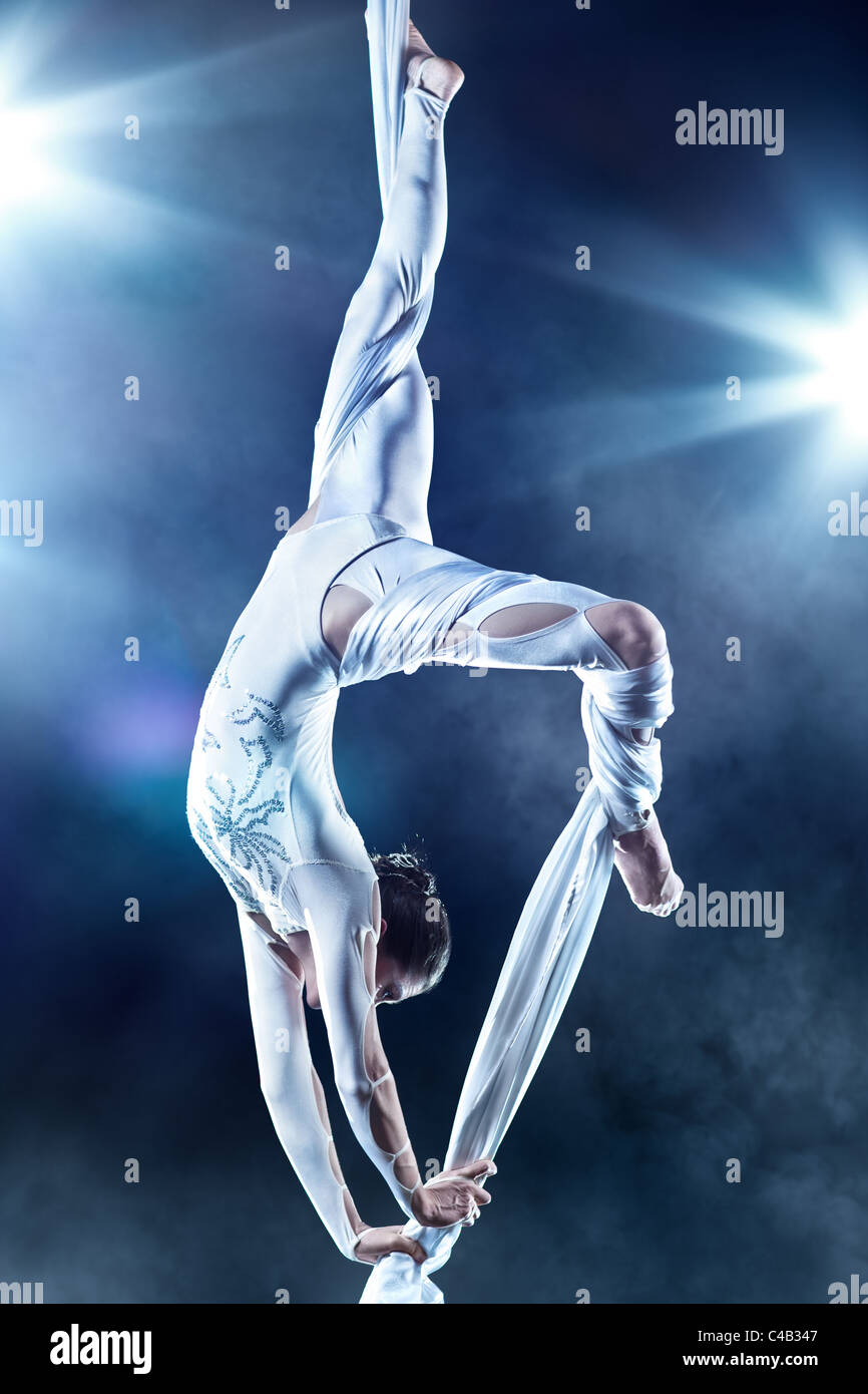 Mujer joven gimnasta. Sobre fondo negro con efecto flash. Foto de stock