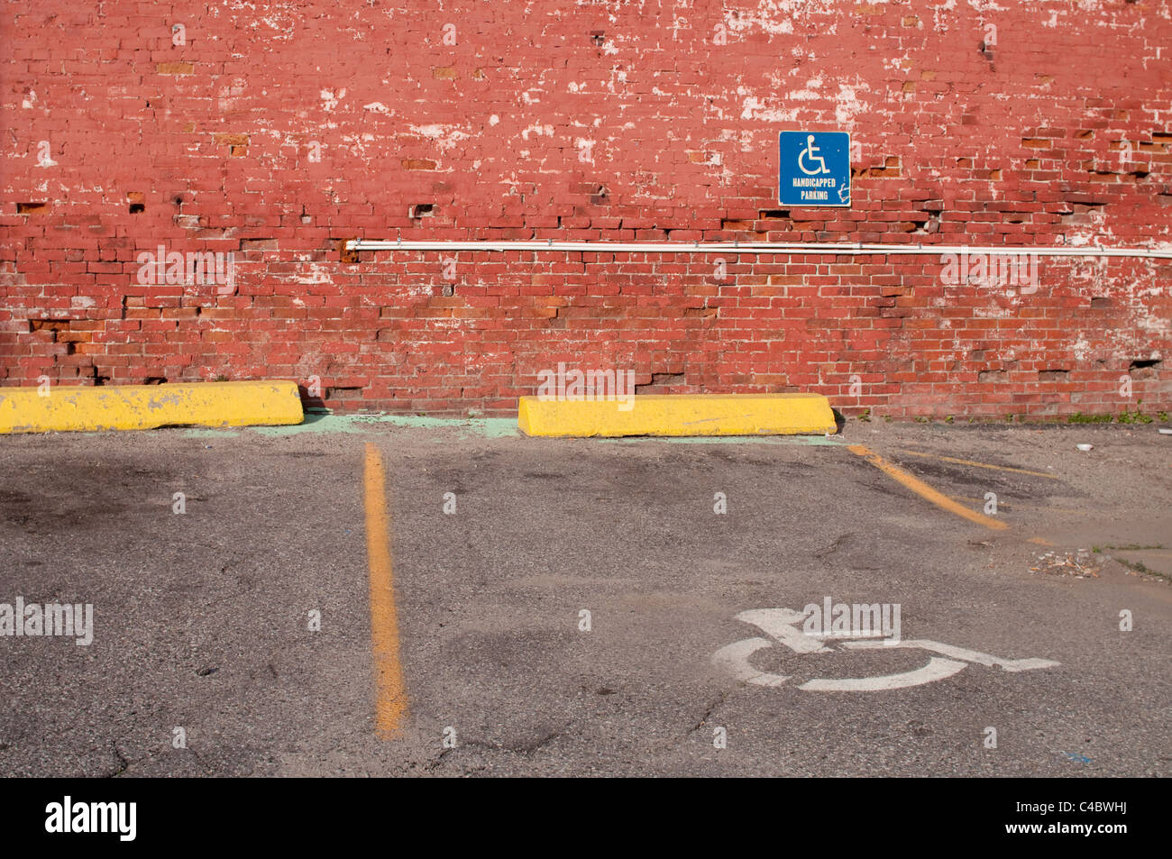 Discapacitados/estacionamiento para discapacitados en los EE.UU. contra una pared de ladrillos en un parking. Foto de stock