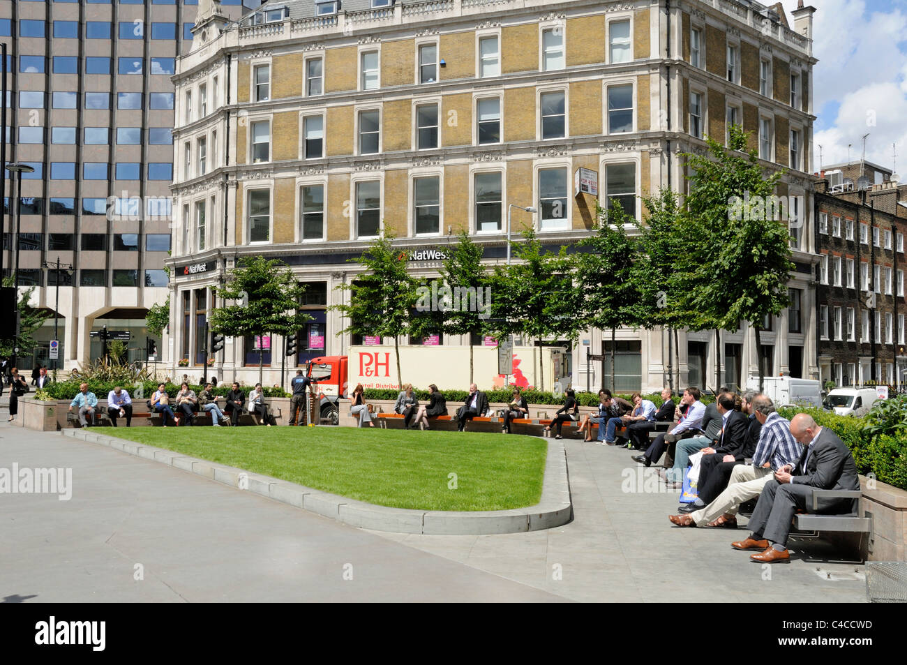 La gente disfruta del sol en una nueva y moderna zona de asientos públicos en forma de triángulo o espacio abierto Holborn Circus London Inglaterra Gran Bretaña UK Foto de stock