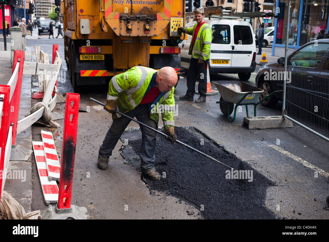 Los obreros la reparación de carreteras dañadas por el tiempo y el tráfico, Glasgow, Escocia Foto de stock