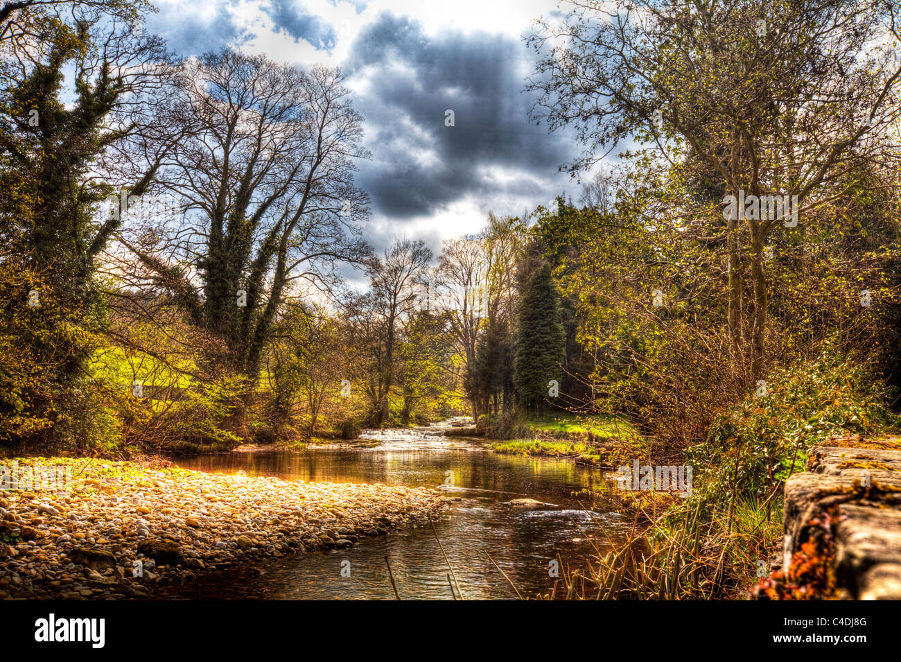 Buckden, Río Wharfe, en Buckden, Upper Wharfedale, Valles de Yorkshire, en el norte de Inglaterra moody cielo reflejándose en el agua Foto de stock