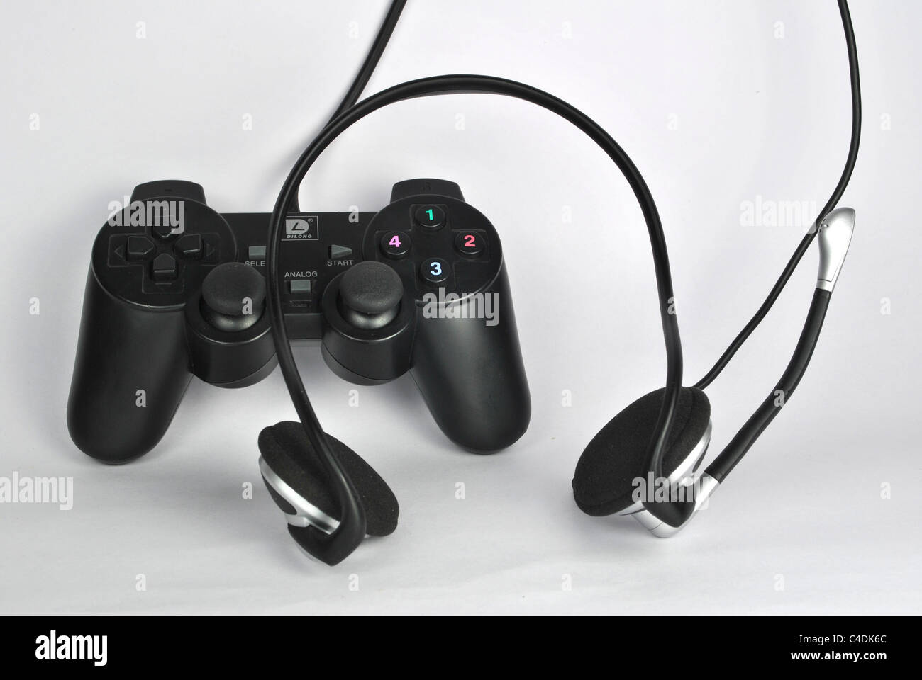 También llamado gamepad joypad o panel de control un tipo de controlador de juego celebrado en la mano sobre fondo blanco con auriculares Foto de stock