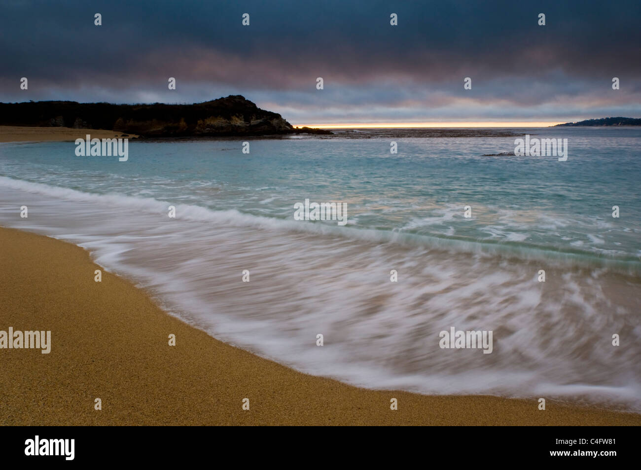 Olas rompiendo en la arena de la playa al atardecer, Carmel River State Beach, California Foto de stock