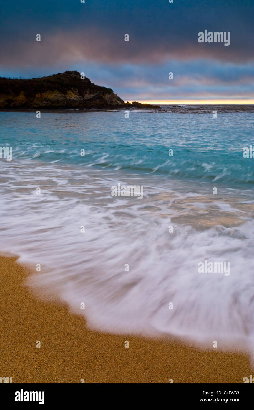 Olas rompiendo en la arena de la playa al atardecer, Carmel River State Beach, California Foto de stock