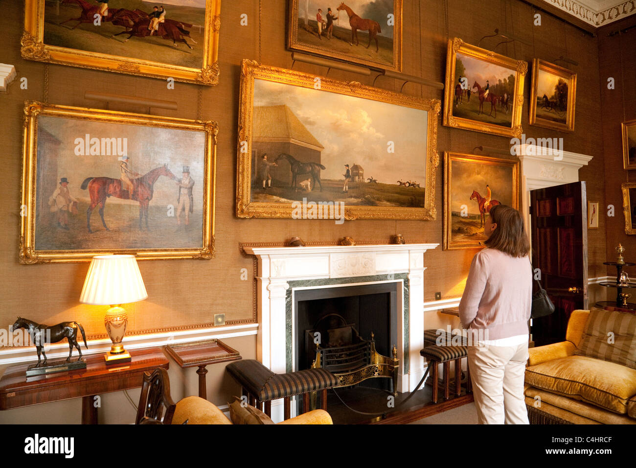 Una mujer mirando la colección de arte histórico en la habitación por la mañana, el Jockey Club, Newmarket Suffolk UK Foto de stock