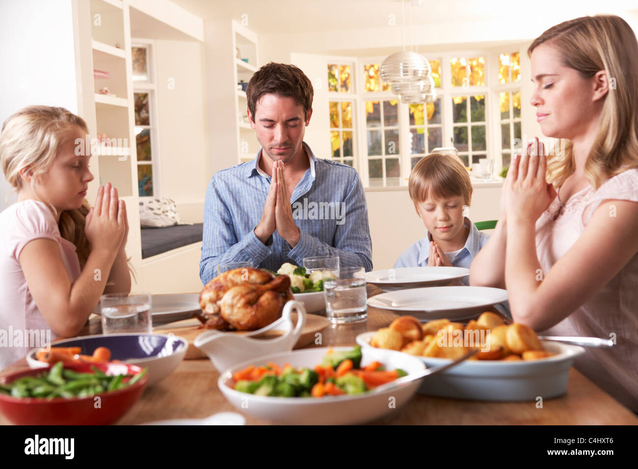 Familia diciendo la oración antes de comer asado de cena Fotografía de