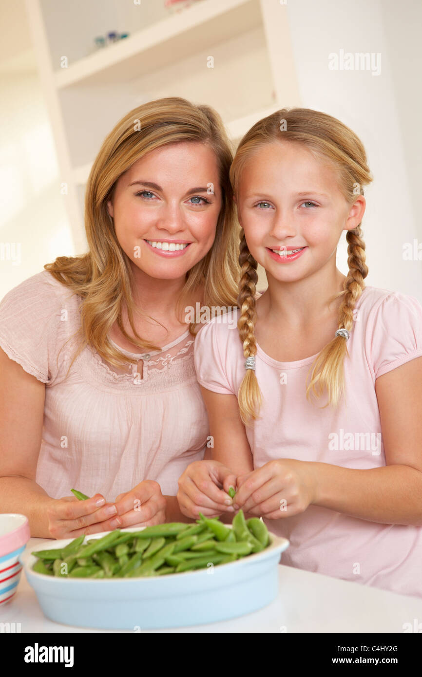 Mujer joven con niño dividiendo el guisante en la cocina Foto de stock