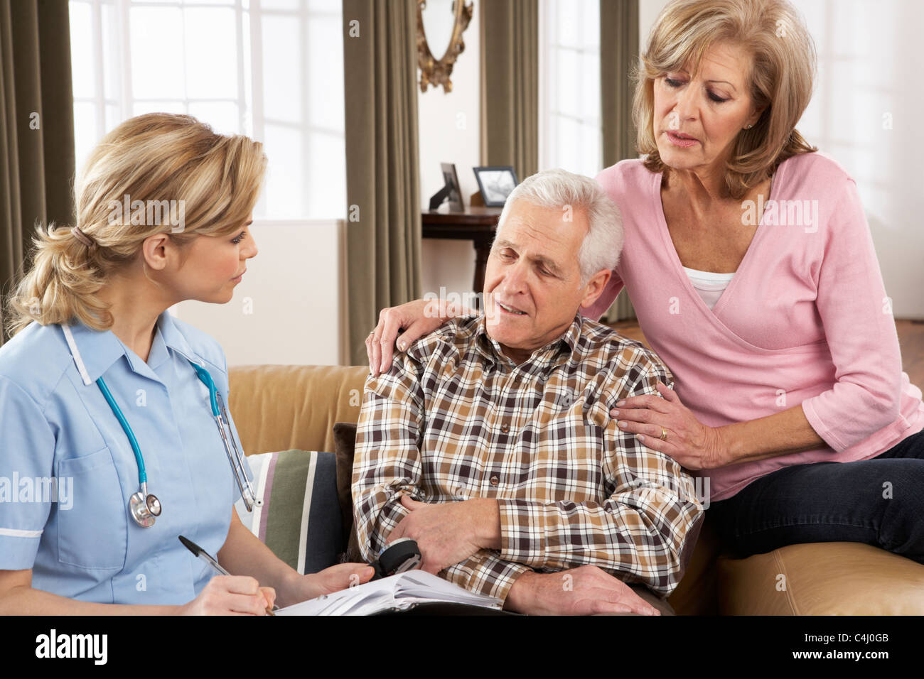 Las parejas ancianas hablando con el visitador de salud en el hogar Foto de stock