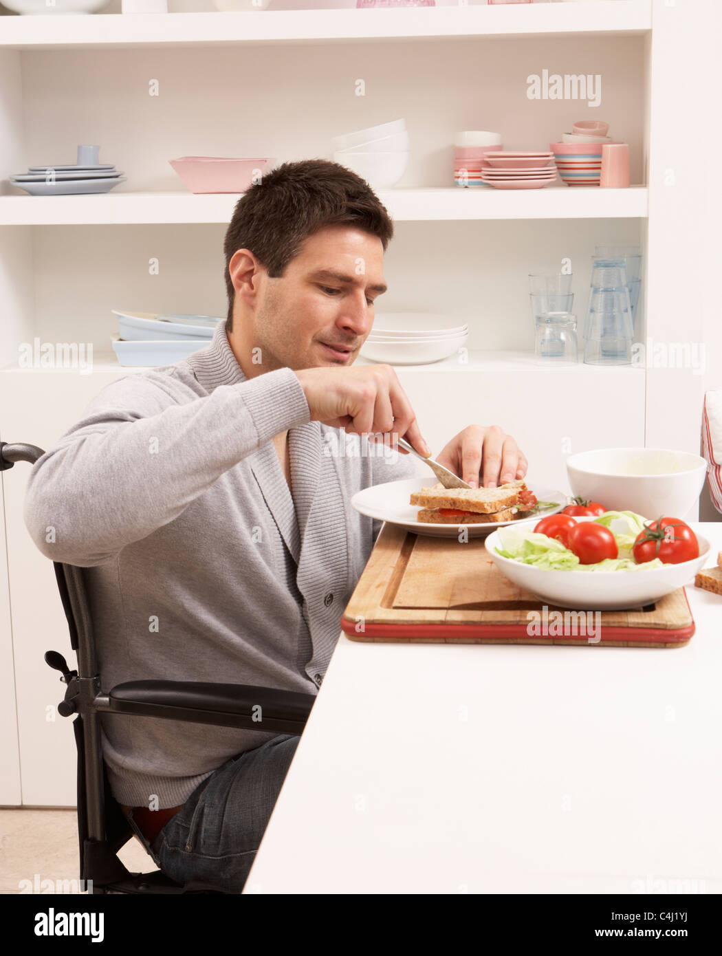 Hombre con discapacidad haciendo Sandwich en Cocina Foto de stock