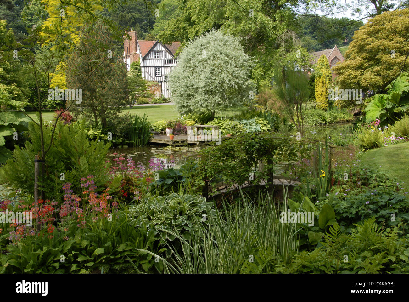 Un paisaje muy completo de un típico jardín campestre inglés,con Tudor House en el fondo,flores y agua Foto de stock