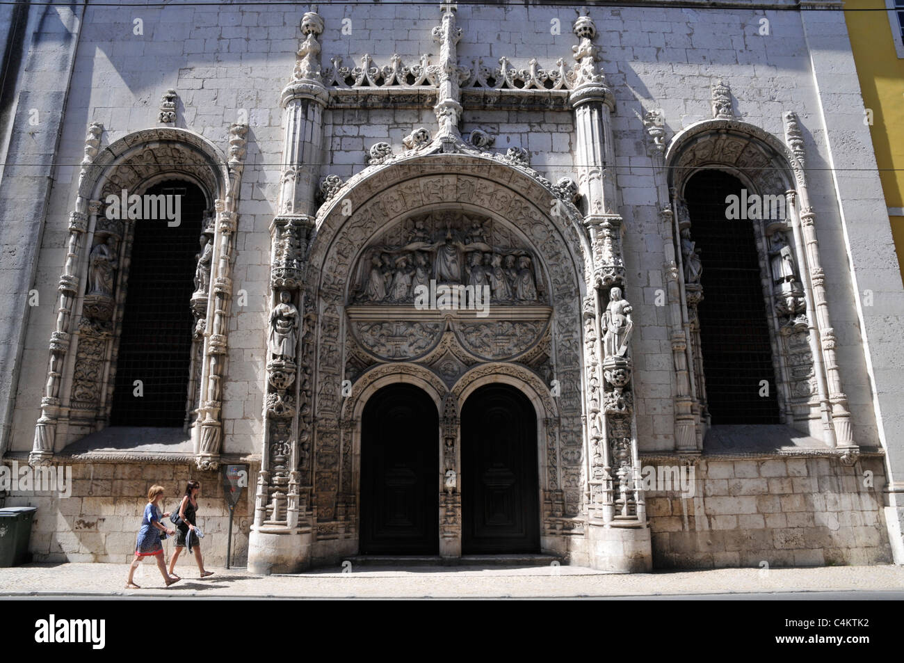 Portal de la iglesia de Nossa Senhora da Conceição Velha, en el centro de Lisboa, Portugal, con dos mujeres turistas que pasan por ahí. Foto de stock