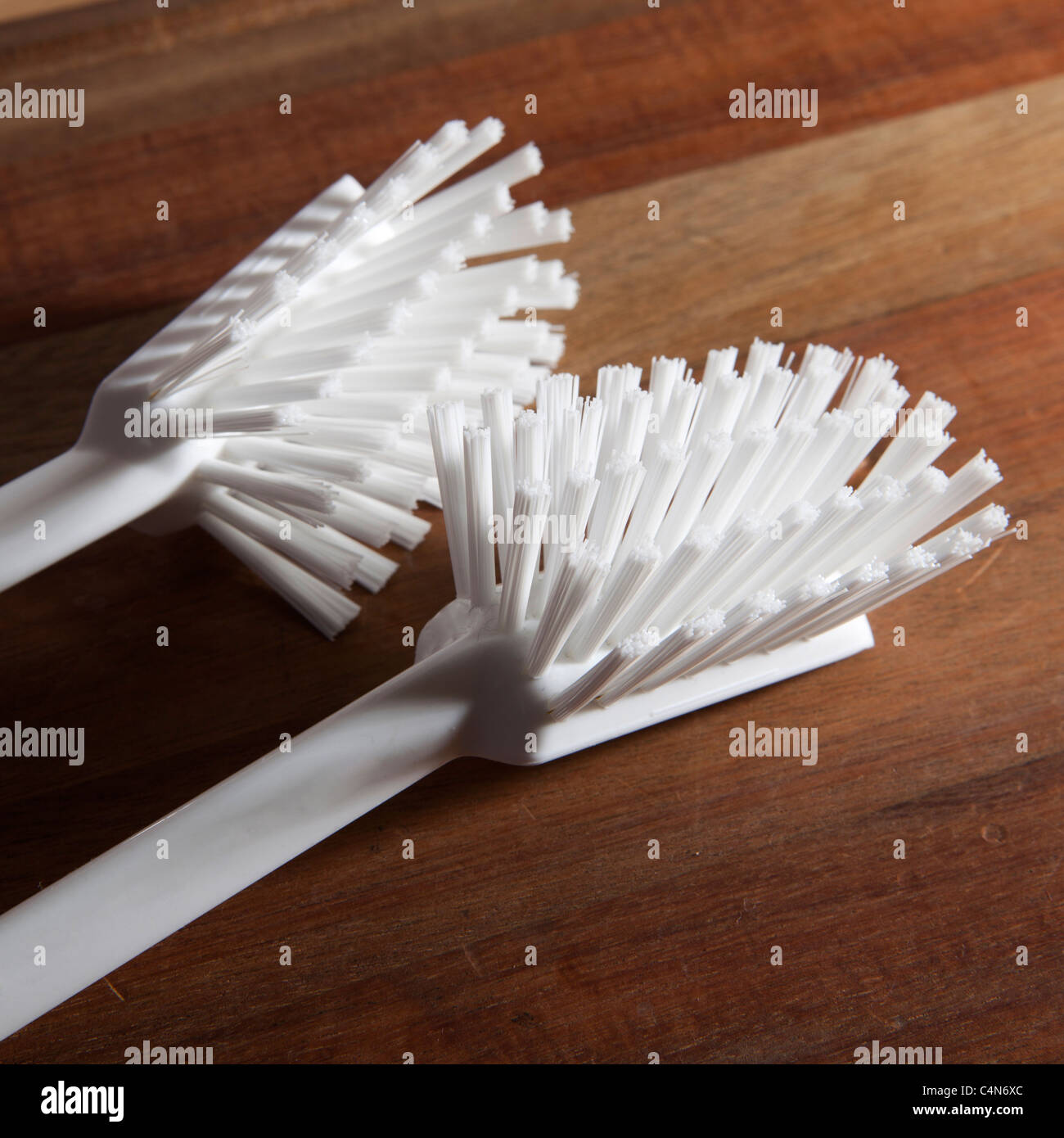 Cepillo de plástico para la vajilla en una mesa de madera Foto de stock