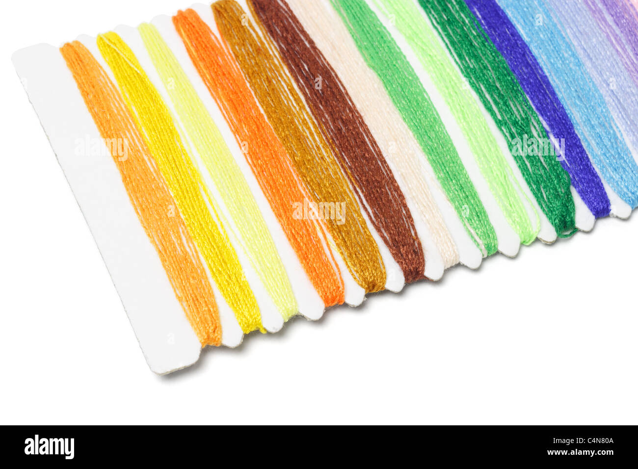 Fila de hilos de coser multicolor sobre fondo blanco. Foto de stock