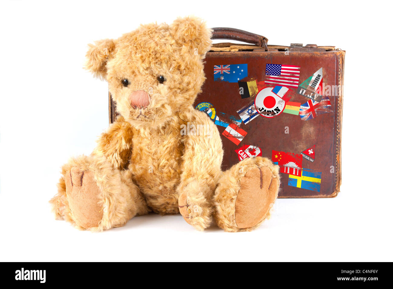 Foto de estudio de un oso de peluche y vintage vieja maleta con pegatinas mundo aislado sobre un fondo blanco. Foto de stock